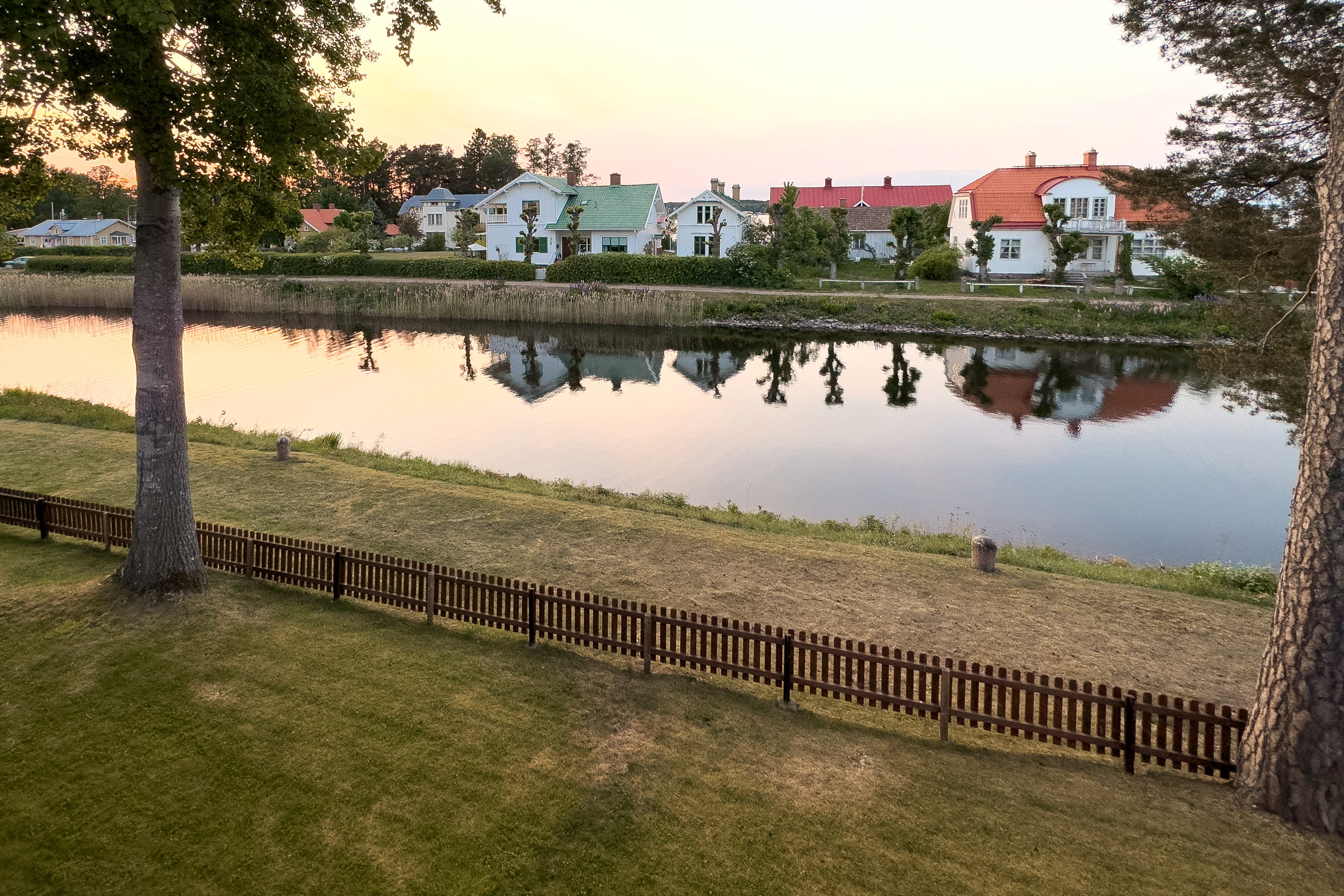 Utsikt över Göta kanal med hus i bakgrunden som speglar sig i vattnet.